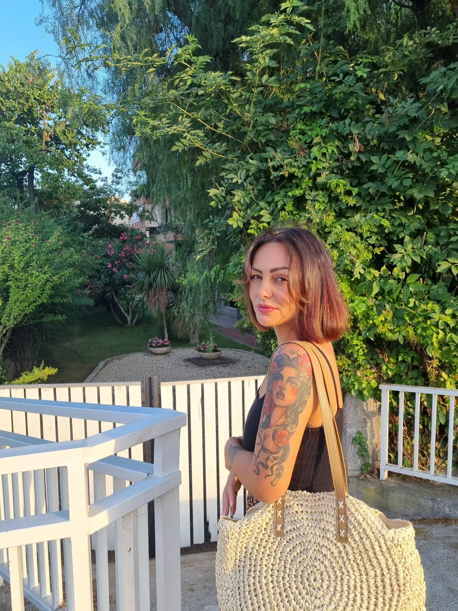 Ann Negreira im Garten mit einer geflochtenen Tasche über der Schulter